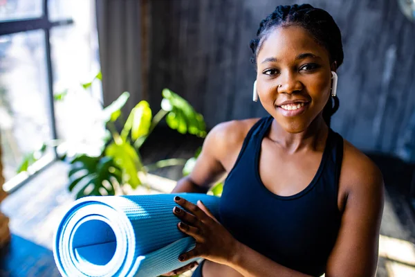 Afrikansk amerikansk kvinna i svart sportig BH med yoga på mattan lyssnar ett ljud meditera mantra — Stockfoto