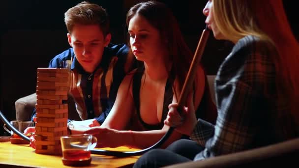 Les jeunes s'amusent à jouer à des jeux de société à une table dans un café — Video