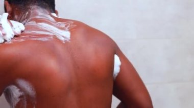 Brezilya 'lı adam beyaz banyoda duş süngeri ile vücudu yıkıyor.