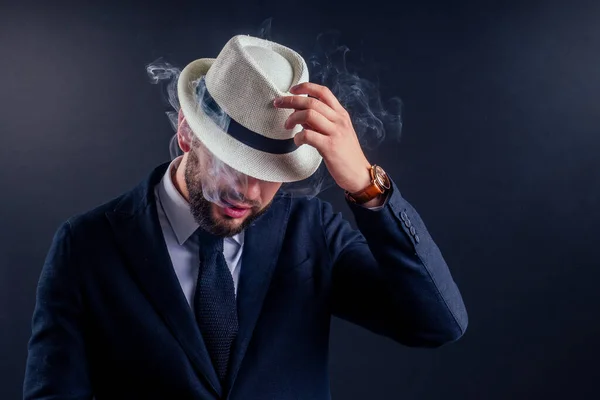 Retrato de un atractivo hombre de negocios con un cigarro en un estudio de fondo negro — Foto de Stock