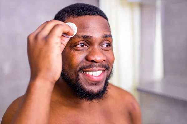 Hombre afroamericano mirándose en el espejo del baño apretando espinilla —  Fotos de Stock