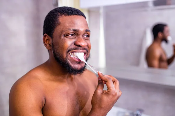 Hombre africa cepillo de dientes en el baño mirando el espejo —  Fotos de Stock