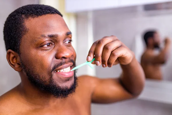 Hombre afroamericano limpiando sus dientes con hilo dental —  Fotos de Stock