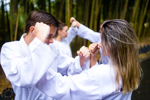 Pessoas chutes altos durante o treinamento de taekwondo ao ar livre fundo de bambu — Fotografia de Stock