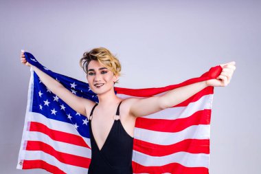Amerikan bayrağına sarılmış rujlu genç bir adamın yakın plan portresi.