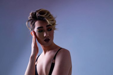 Lüks sarı saçlı ve beyaz duvarlı muhteşem makyajlı Asyalı bir adam. Arka plan tutkusu. Kameraya bak.