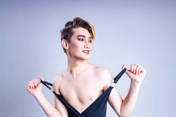 блондин с макияжем на лице позирует в студии на белом фоне