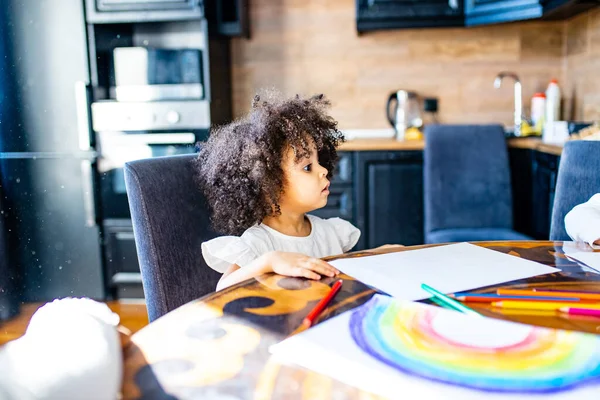 Africana brasileña niña pintando arco iris sobre papel en la mesa en casa — Foto de Stock