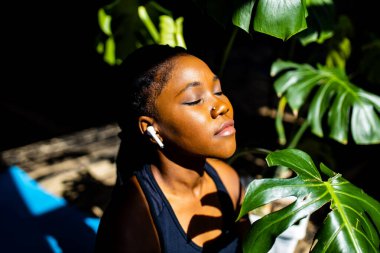 Siyah spor takım elbiseli melez sağlıklı bir kadın evdeki spor salonunda panoramik pencerelerin arka planına karşı çalışıyor.