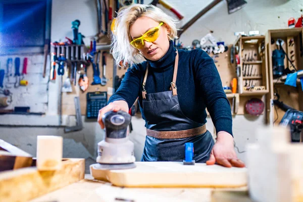 Blond vrouwelijke timmerman met behulp van tools voor haar werk in een houtwerkplaats — Stockfoto