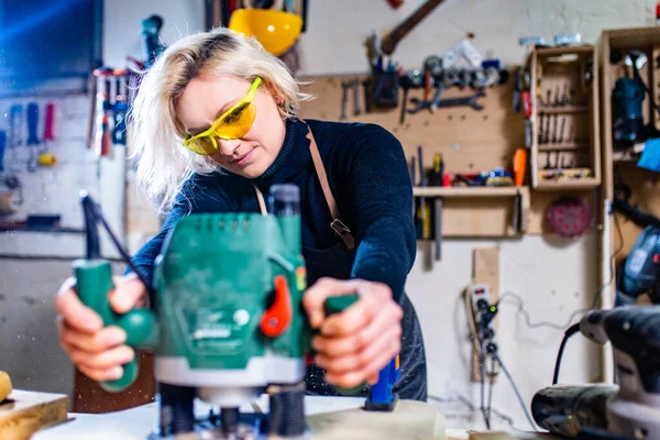 Blondýnka žena tesař pomocí nástrojů pro její práci v obchodě se dřevem — Stock fotografie