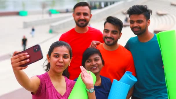 Cuatro personas indias calentándose al aire libre en ropa deportiva haciendo selfie en la cámara del teléfono inteligente — Vídeos de Stock