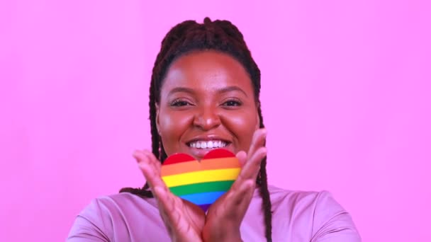 Afro amerikansk kvinna som håller ett hjärta form i rosa studio bakgrund — Stockvideo