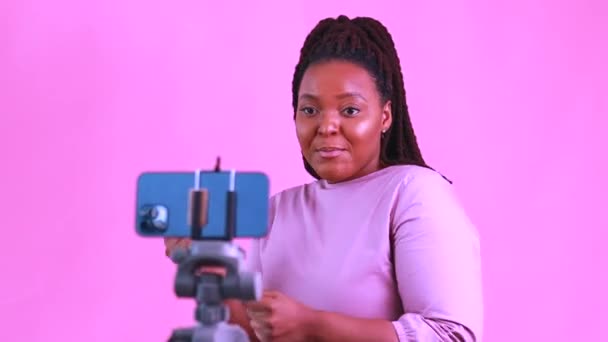 Mulher hispânica com tranças frescos tranças usar vestido rosa no estúdio conversando com seus assinantes por câmera de telefone — Vídeo de Stock