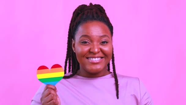 Mujer afroamericana sosteniendo una forma de corazón en fondo de estudio rosa — Vídeo de stock
