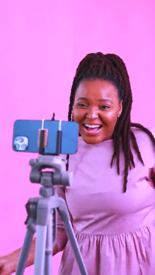 Hispanic woman with cool dreadlocks pigtails wear pink dress in studio chatting with her subscribers by phone camera — Stock Video