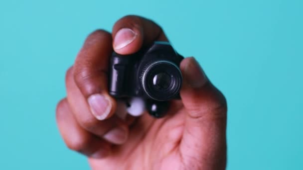 Mini cámara en la mano del hombre afroamericano en estudio azul — Vídeos de Stock