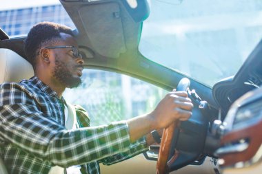 Şık ekose takım elbiseli Latin bir adam lüks spor arabalarda gözlük takıyor.