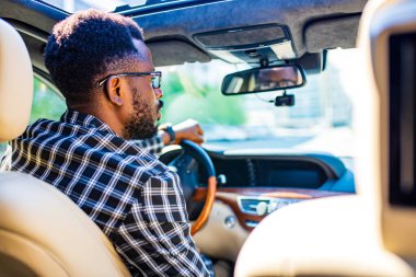 Şık ekose takım elbiseli Latin bir adam lüks spor arabalarda gözlük takıyor.