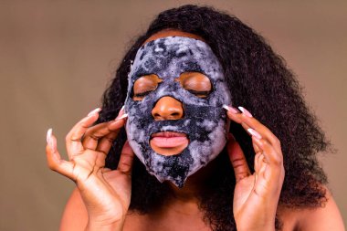 Kahverengi arka planda, yüzünde baloncuk maskesi olan genç bir kadın.