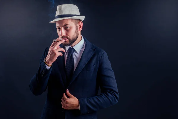 Retrato de un atractivo hombre de negocios con un cigarro en un estudio de fondo negro — Foto de Stock