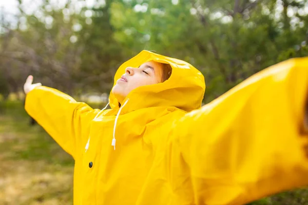 Sonriente adolescente usando impermeable al aire libre en día lluvioso — Foto de Stock