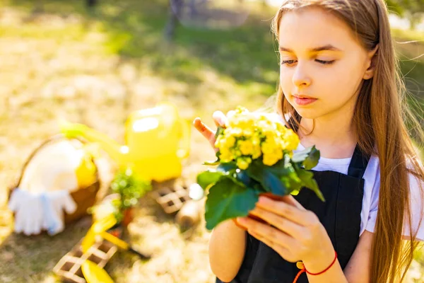 Adolescente chica en negro delantal jardinería en el jardín del patio trasero — Foto de Stock