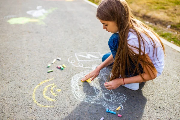 Yaratıcı zanaat hobisi olan küçük bir kız asfalta tebeşir arabalı elektro çiziyor, çevre dostu, yaz günü parkta enerji tasarrufu yapıyor. — Stok fotoğraf