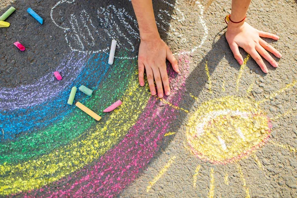 Teenager-Mädchen zeichnet an einem Sommertag eine regenbogenfarbene Kreide auf den Asphalt — Stockfoto