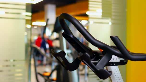 Ciclismo en el entrenador de la máquina haciendo ejercicio en el gimnasio — Vídeos de Stock