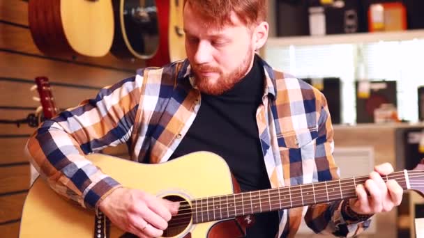 Rothaariger Ingwermann wählt hochwertige Akustikgitarre im Gitarrenladen — Stockvideo