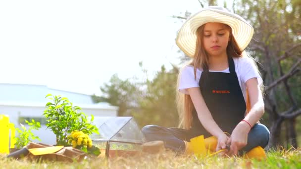 검은 앞치마와 노란 고무 구두를 신고 정원에서 돌보고 있는 아름다운 십 대 소녀 — 비디오