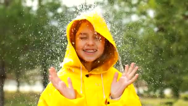 Menina adolescente sorrindo vestindo capa de chuva ao ar livre em dia chuvoso — Vídeo de Stock