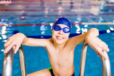 Gözlüklü, yüzme şapkalı, Down sendromlu çocuk.