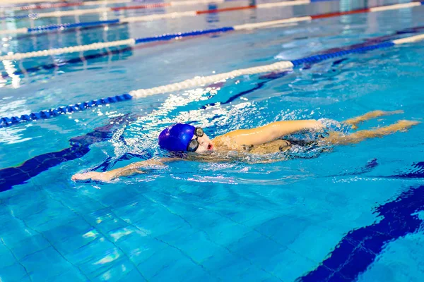 Ragazzo disabile con sindrome di Down in cuffia da nuoto indossando occhiali in piscina — Foto Stock