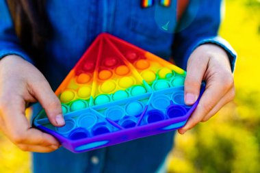 Latin kökenli liseli kız öğrenci üniforma giyiyor ve dışarıda pop it oyuncağı oynuyor.