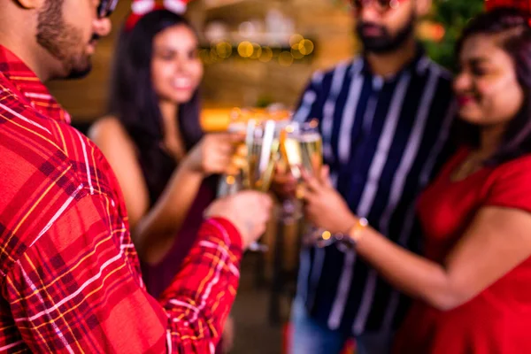 Gruppo di quattro amici indiani tifo con champagne flauti e cercando felice mentre hanno festa in cucina a rimanere a casa quarantena partito focolaio di virus corona — Foto Stock