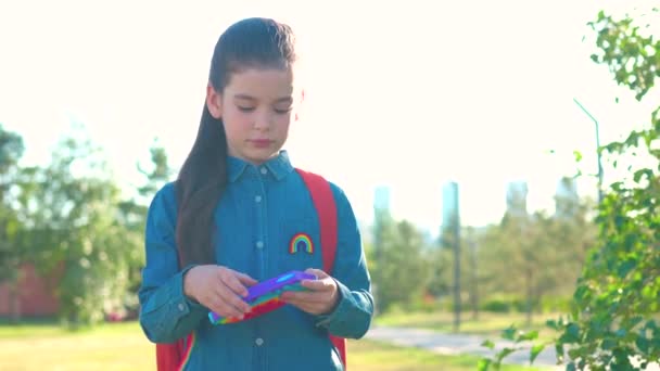 Preteen latin copil scolarita student poartă uniformă și rucsac în aer liber joc pop it jucărie . — Videoclip de stoc