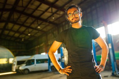 Otomobil tamircisi gün batımında atölyesinde duruyor.