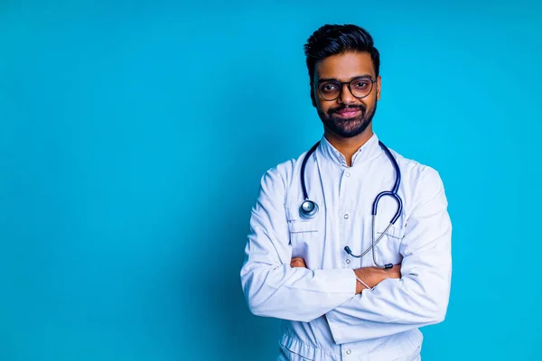 Mladý latinsky hispánský medik muž nosit brýle s stetoskopem v modrém studiu pozadí zdi — Stock fotografie