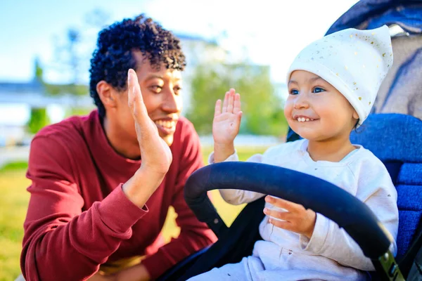 Família de raça mista pai feliz com a menina no carrinho no parque de verão — Fotografia de Stock