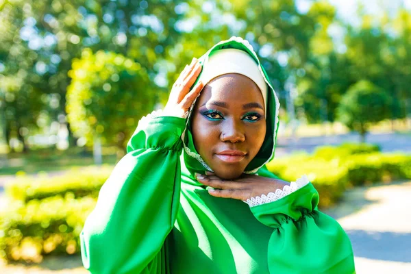 Современная аутентичная смешанная раса ислам женщина в зеленом хлопчатобумажном хиджабе с великолепным макияжем на открытом воздухе в летнем парке — стоковое фото