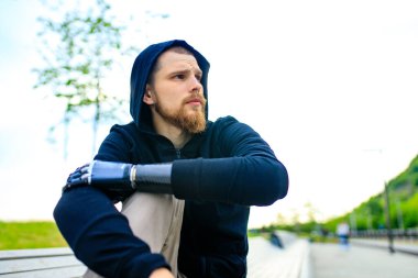 Spor kıyafetleri içinde kol protezi olan bir adam sabah sporu için dışarıda çalışmaya hazır. Engelli spor konsepti
