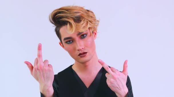 Fuck off man with gorgeous make up and hairstyle in studio white background showing middle finger — Stock video