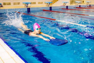 Gözlüklü, yüzme şapkalı, Down sendromlu çocuk.