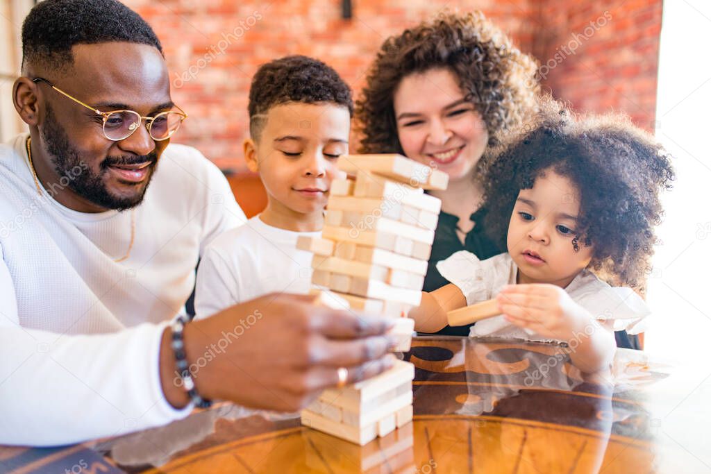 african mixed race family palying a round of jenga in cozy living room