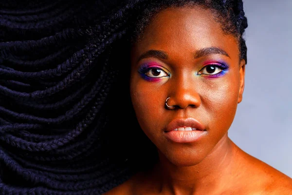 Mulher hispânica com nariz piercing e arco-íris colorido compõem em fundo estúdio azul — Fotografia de Stock