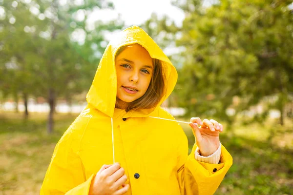 ยิ้มสาววัยรุ่นสวมเสื้อกันฝนกลางแจ้งในวันที่ฝนตก — ภาพถ่ายสต็อก