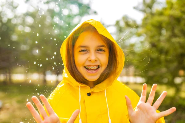 Lächelndes Teenagermädchen im Regenmantel an einem regnerischen Tag — Stockfoto