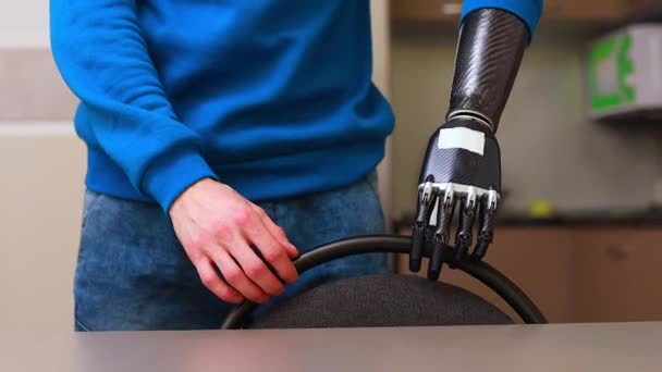 Fiatal férfi kiborg kezét mozgatja a széket, és otthon ül a konyhában — Stock videók